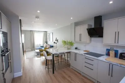 a kitchen with white cabinets and a table and chairs at Stylish and Modern 2 Bed House in Glasgow