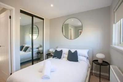 a bedroom with a white bed and a mirror at Stylish and Modern 2 Bed House in Glasgow