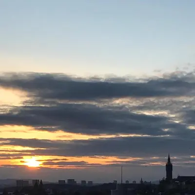 a sunset over a city with a clock tower at Duplex Apartment in Glasgow
