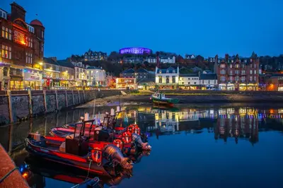 a group of boats sitting in the water at night at Exceptional 2BD Apt - next to ferry & train station in Oban