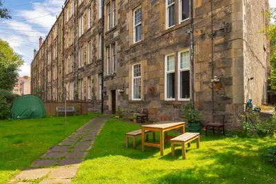 a garden with a table and benches in front of a building at Woodford Street in Mansewood