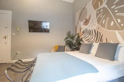 a bedroom with a white bed with a painting on the wall at Cosy Palm Studio West End - Pass the Keys in Glasgow