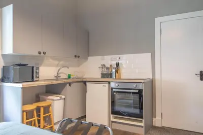 a kitchen with white cabinets and a sink and a stove at Cosy Palm Studio West End - Pass the Keys in Glasgow