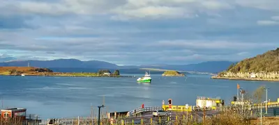 a green and white boat in a large body of water at Three Oban in Oban