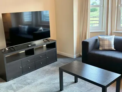 a living room with a tv and a couch and a coffee table at Kingfisher Apartment in Dunfermline