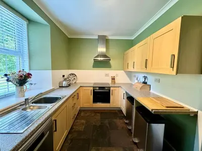 a kitchen with wooden cabinets and a sink at Country Cottage on Private Estate in Minishant