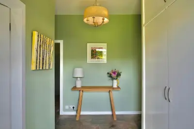 a hallway with a table with a lamp and green walls at Country Cottage on Private Estate in Minishant