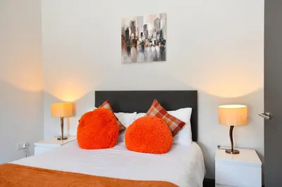 a bedroom with a bed with two orange pillows on it at Diamond House - 4 bedroom luxury home in Airdrie