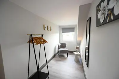 a living room with a chair and a mirror at Diamond House - 4 bedroom luxury home in Airdrie