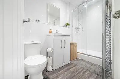 a white bathroom with a toilet and a shower at Super Prime Abbey Free Parking by TBA in Dunfermline