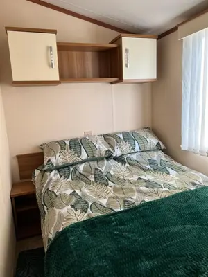 a bedroom with a bed with a green comforter at Maneight Fir View with hot tub in Dalleagles