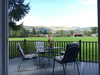 a patio with a table and chairs and a view of a field at Thistle Lodge in Dollar