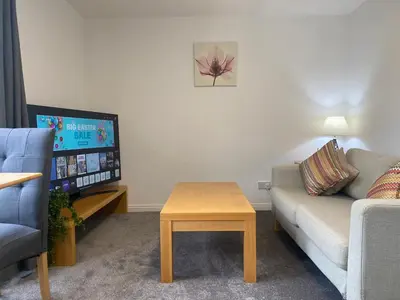 a living room with a couch and a table and a tv at Prime City Centre - Ground Floor Parking by TBA in Dunfermline