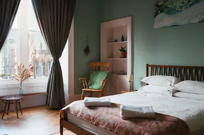 a bedroom with a bed and a chair and a window at Beautiful central Edinburgh Apartment in Edinburgh