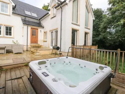 a hot tub on a deck in front of a house at Taighean Anndra in Killin