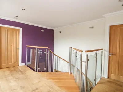 an empty hallway with purple walls and wooden stairs at Taighean Anndra in Killin
