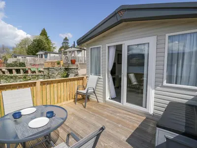 a patio with a table and chairs on a deck at 11A Mansion View in Helensburgh