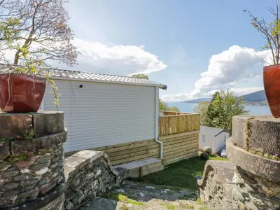 a house with a garage and a stone wall at 11A Mansion View in Helensburgh