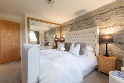 a bedroom with a white bed and a large mirror at Bungalow with Hot Tub, BBQ Hut, Golf Net , Large Garden & Play Area in Maybole