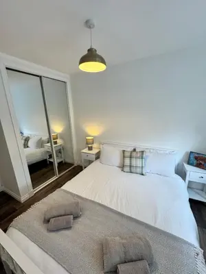 a bedroom with a large white bed with a mirror at Inchcruin Apartment - Macaulay Letting in Bonhill