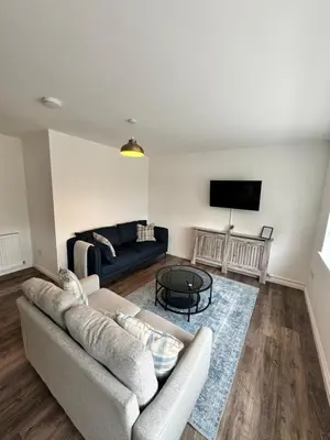 a living room with a couch and a tv at Inchcruin Apartment - Macaulay Letting in Bonhill