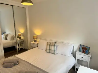 a bedroom with a white bed and a mirror at Inchcruin Apartment - Macaulay Letting in Bonhill