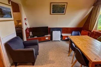 a living room with a table and chairs and a television at 1 Bedroom Cabin with Mountain & Loch Views - Quiet Location between Glencoe & Ben Nevis in Corran