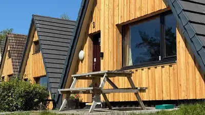 a house with a bench in front of it at 1 Bedroom Cabin with Mountain & Loch Views - Quiet Location between Glencoe & Ben Nevis in Corran
