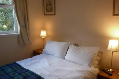 a bedroom with a bed with white sheets and two lamps at Highland Snug in Dunoon
