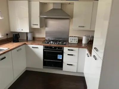 a kitchen with white cabinets and a stove top oven at Holytown Homes in Holytown