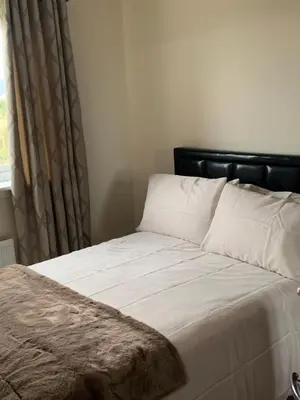 a bed with a black head board and a window at Holytown Homes in Holytown