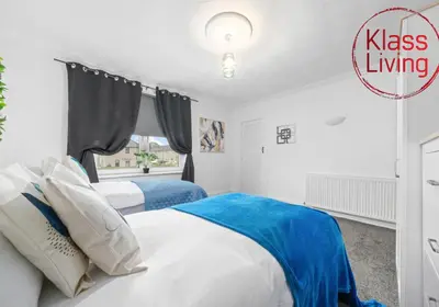 two beds in a white bedroom with a window at Fraser House by Klass Living Rutherglen in Glasgow