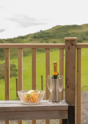 a table with two glasses and a bottle of wine at Countryside Farm Pod on Isle of Seil - A in Balvicar