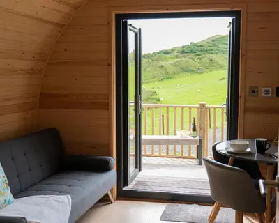 a living room with a couch and a large sliding glass door at Countryside Farm Pod on Isle of Seil - A in Balvicar