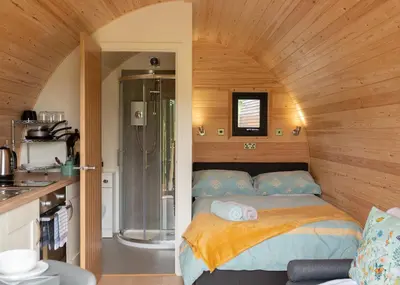 a small bedroom with a bed and a shower at Countryside Farm Pod on Isle of Seil - B in Balvicar