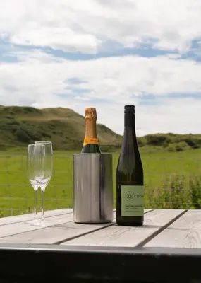 a bottle of wine and a glass on a table at Countryside Farm Pod on Isle of Seil - B in Balvicar