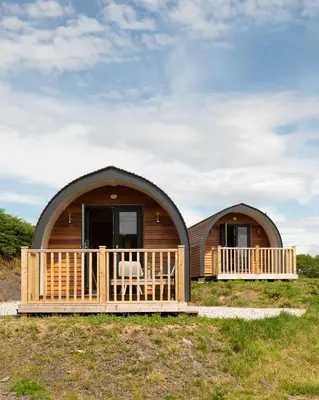 a log cabin with a porch and a deck at Countryside Farm Pod on Isle of Seil - B in Balvicar
