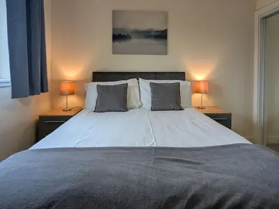 a bedroom with a large bed with two lamps at Parkgate 2 bed, private parking, Rosyth M90 in Rosyth
