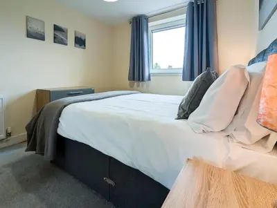 a bedroom with a large bed with blue curtains at Parkgate 2 bed, private parking, Rosyth M90 in Rosyth