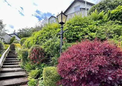 a garden with a street light and colorful bushes at St Abbs in Innellan