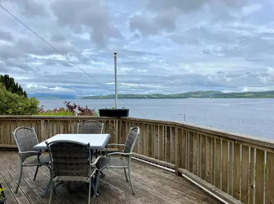 a table and chairs on a deck overlooking a body of water at St Abbs in Innellan