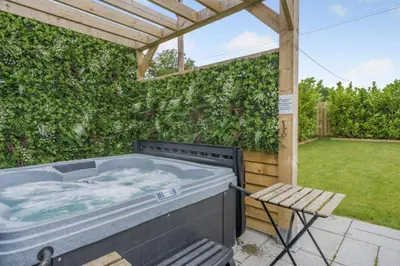 a hot tub in a backyard with a pergola at Cottage with Hot Tub near Knockhill in Saline