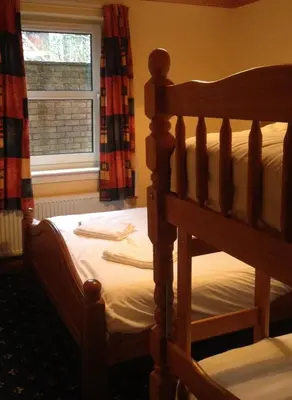 a bedroom with a wooden bed and a window at Twin Lions Hotel in Edinburgh