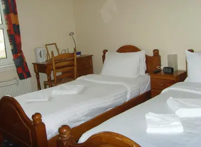 a bedroom with two beds with white sheets and a desk at Twin Lions Hotel in Edinburgh
