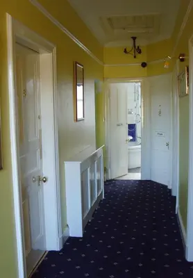a hallway with yellow walls and a room with a fireplace at Twin Lions Hotel in Edinburgh