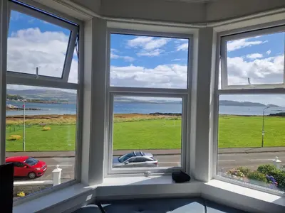 a room with three windows with a view of the ocean at Fairview Millport in Millport