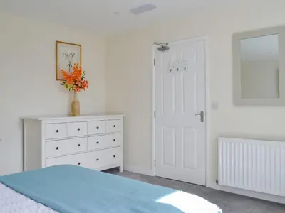 a bedroom with a bed and a dresser and a door at Oak -Apartment 4 in Aberfoyle