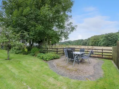 a table and chairs in a yard with a fence at The Barn at Daldorch in Mauchline