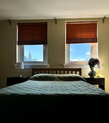 a bedroom with two windows and a bed with blue sheets at Two bedroom maisonette in the heart of the West End in Glasgow