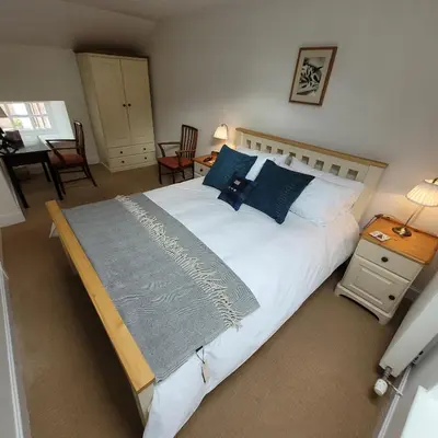 a bedroom with a large white bed with blue pillows at Loch Lomond Finnich Cottages in Drymen